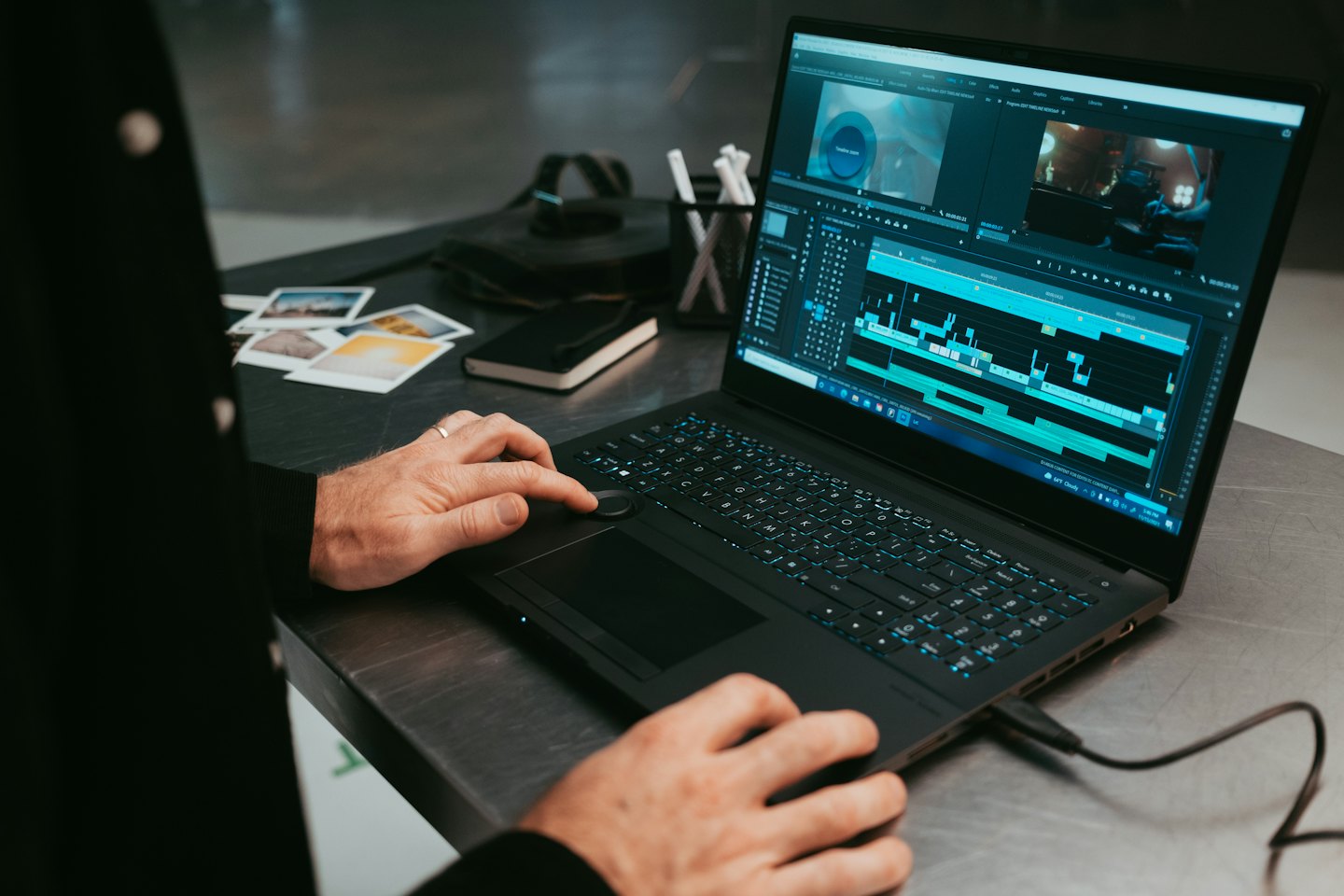 Hands editing video footage on a laptop computer.